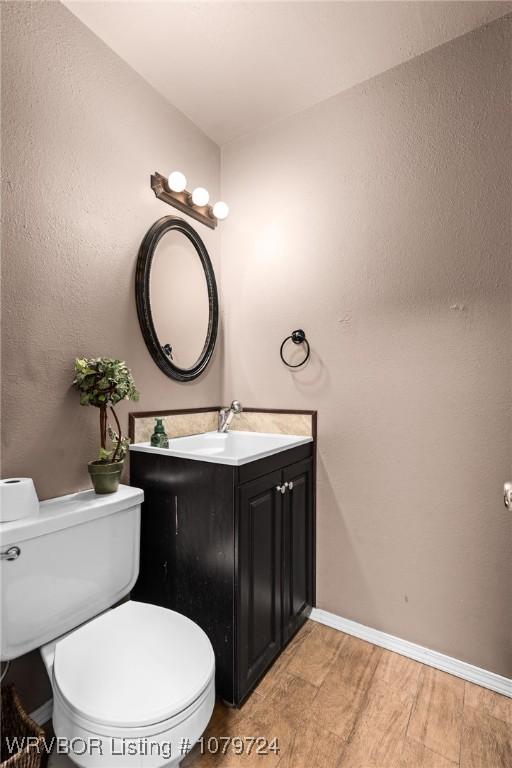 bathroom featuring vanity, toilet, wood finished floors, and baseboards