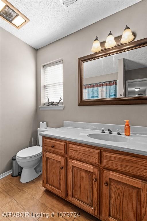full bathroom featuring toilet, a textured ceiling, and vanity