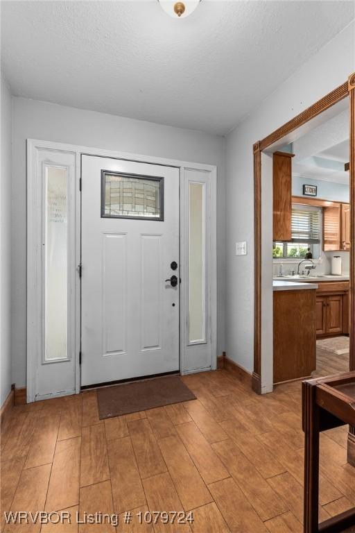 foyer with baseboards and light wood-style floors
