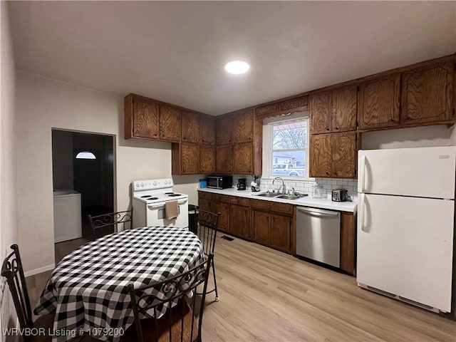 kitchen with white appliances, a sink, light countertops, light wood-type flooring, and backsplash