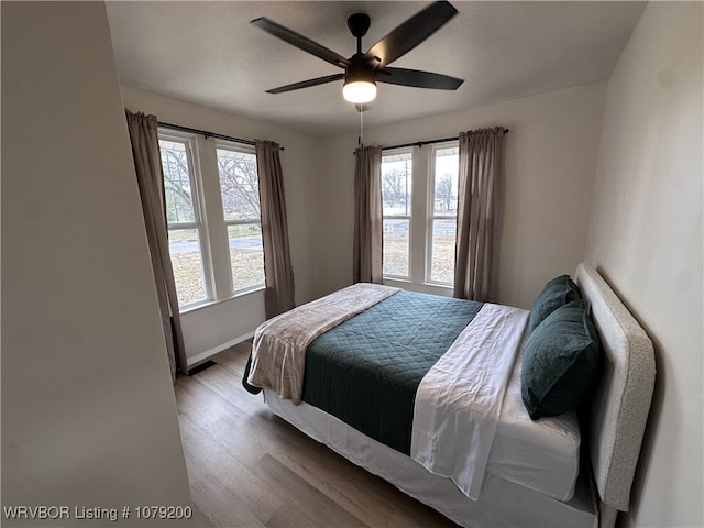 bedroom featuring a ceiling fan, baseboards, and wood finished floors