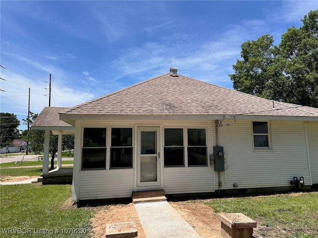 back of property with a yard and roof with shingles