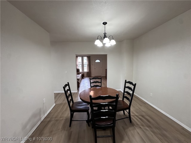 dining room with dark wood-type flooring, a notable chandelier, and baseboards