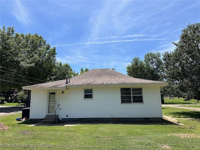 rear view of property with entry steps, crawl space, roof with shingles, and a yard