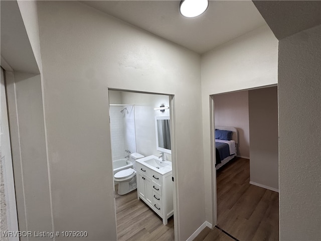 ensuite bathroom with shower / bath combination, toilet, vanity, wood finished floors, and baseboards