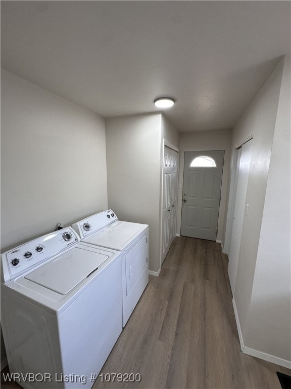 laundry area with laundry area, independent washer and dryer, baseboards, and wood finished floors