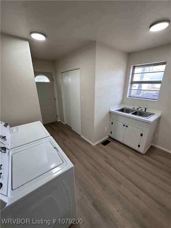 laundry room featuring a sink, wood finished floors, washer and dryer, laundry area, and baseboards