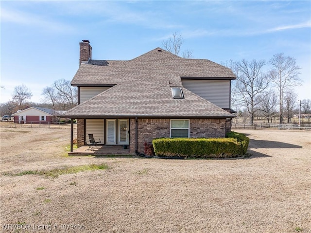 exterior space with a shingled roof, fence, and brick siding