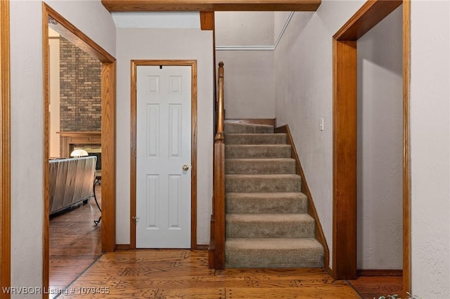 staircase with a fireplace and wood finished floors