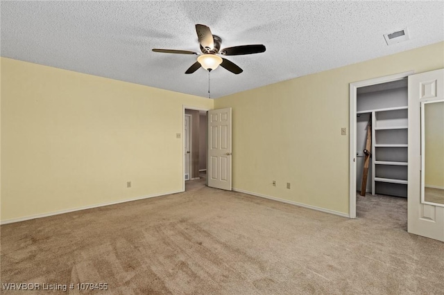 unfurnished bedroom with carpet, visible vents, a spacious closet, and a textured ceiling