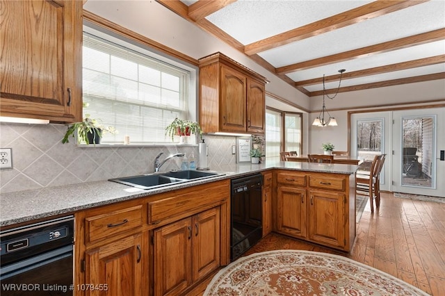 kitchen with black dishwasher, brown cabinets, a sink, plenty of natural light, and a peninsula