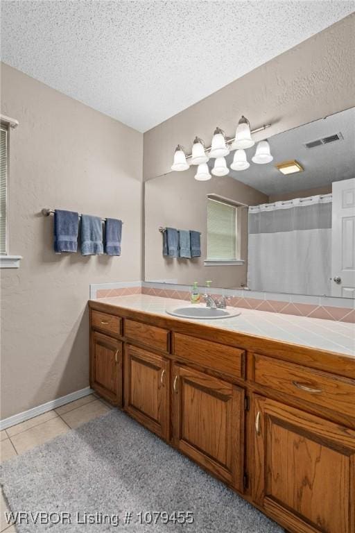 full bathroom with visible vents, a textured ceiling, vanity, and tile patterned floors