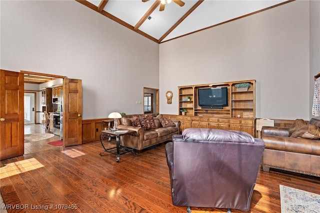 living area featuring hardwood / wood-style flooring, ceiling fan, high vaulted ceiling, and wainscoting