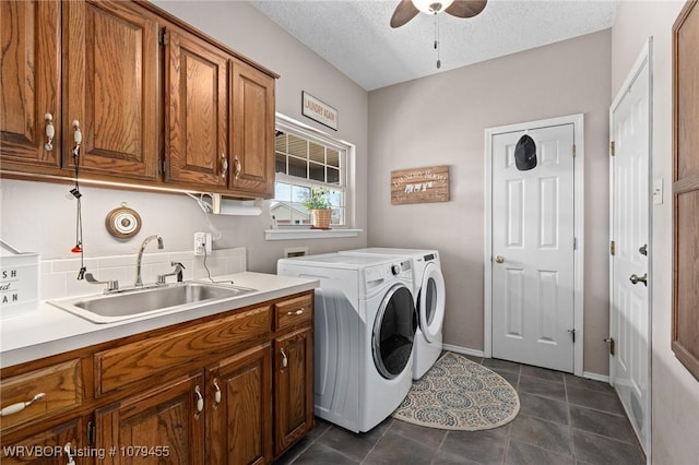 laundry area featuring washer and clothes dryer, cabinet space, a sink, a textured ceiling, and ceiling fan