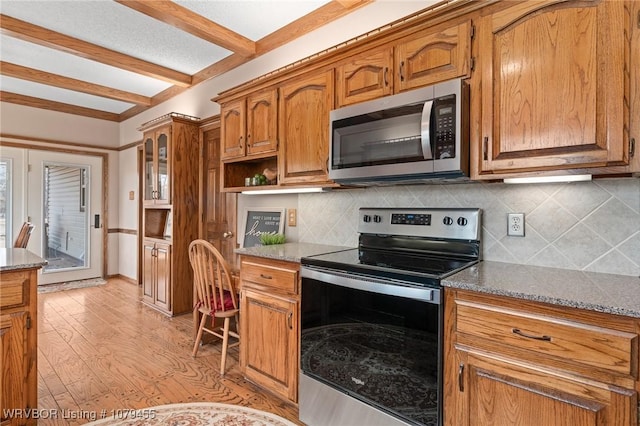 kitchen featuring light wood-style floors, appliances with stainless steel finishes, brown cabinetry, and beamed ceiling