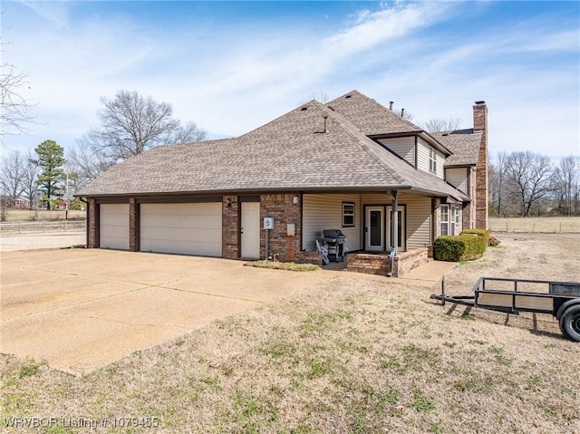 exterior space featuring brick siding, a chimney, a shingled roof, concrete driveway, and an attached garage