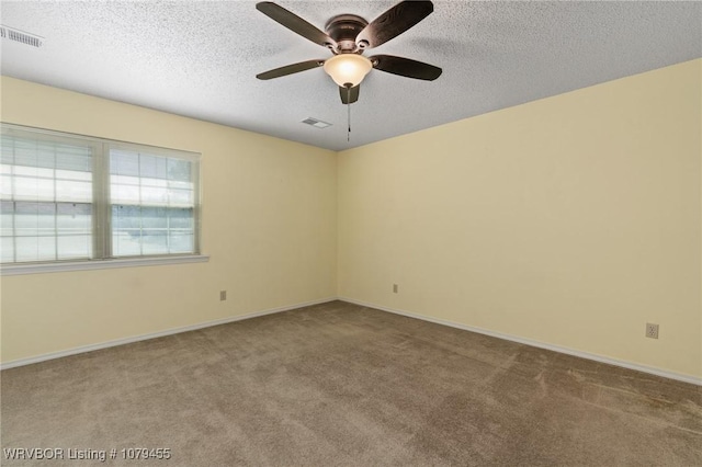 carpeted empty room featuring baseboards, ceiling fan, visible vents, and a textured ceiling