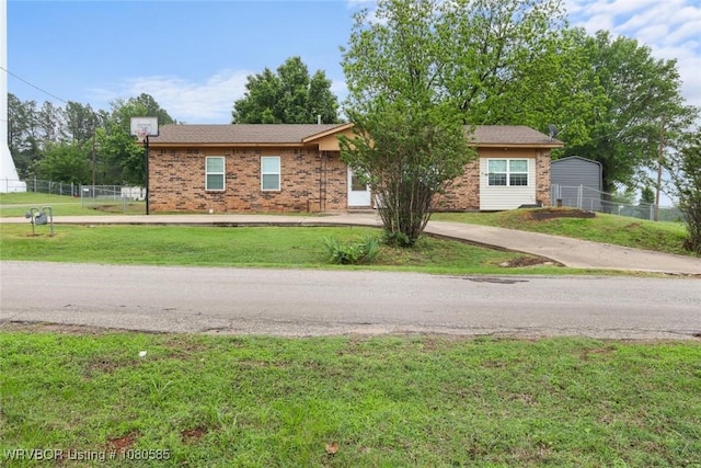 ranch-style house featuring fence, concrete driveway, a front yard, and brick siding