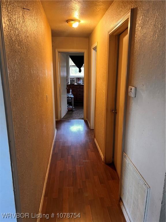 hall with dark hardwood / wood-style floors and a textured ceiling