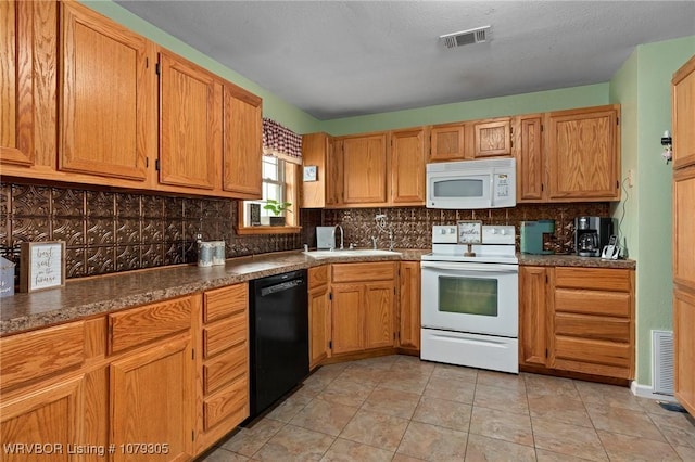 kitchen with decorative backsplash, white appliances, visible vents, and a sink