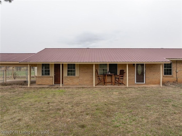 view of front of house with brick siding, metal roof, a front lawn, and fence