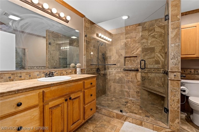 full bath featuring a stall shower, toilet, vanity, and ornamental molding