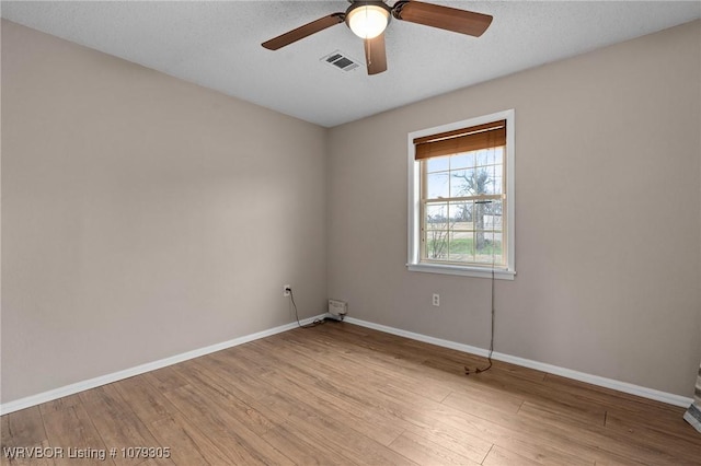 spare room with ceiling fan, wood finished floors, visible vents, and baseboards