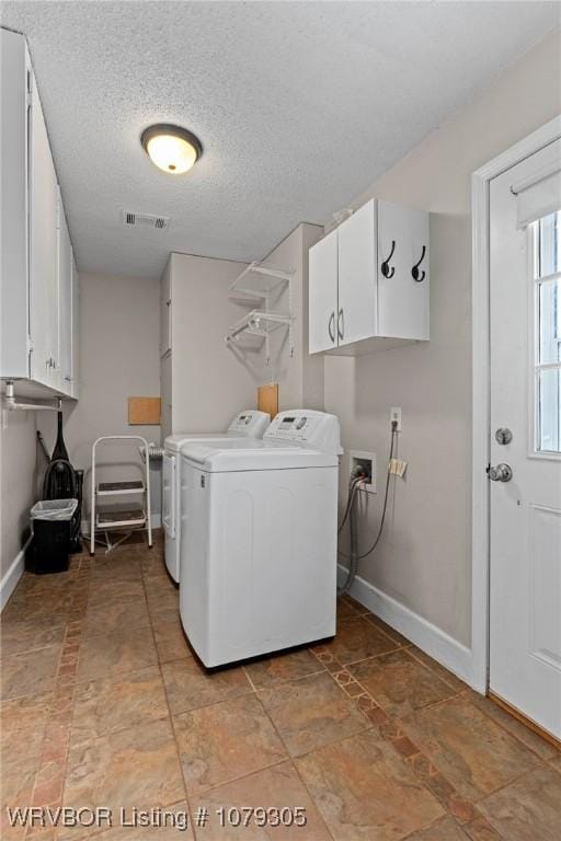 laundry room with washing machine and dryer, cabinet space, a textured ceiling, and baseboards