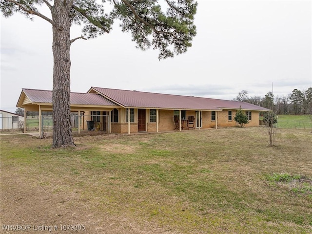 ranch-style home featuring a front yard, brick siding, and metal roof