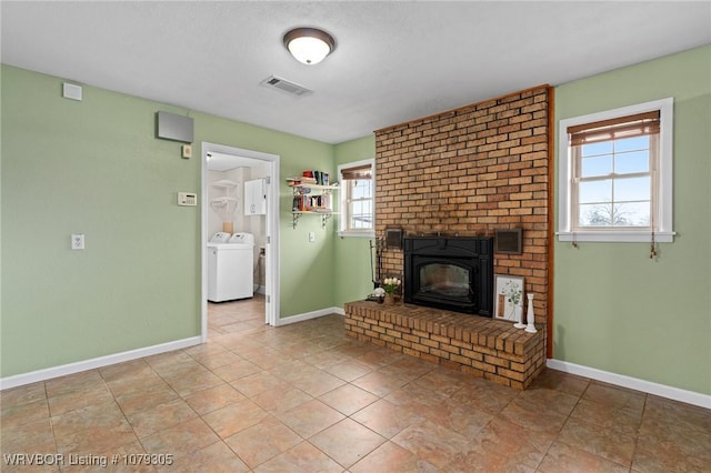 unfurnished living room featuring visible vents, baseboards, washer / dryer, and a fireplace