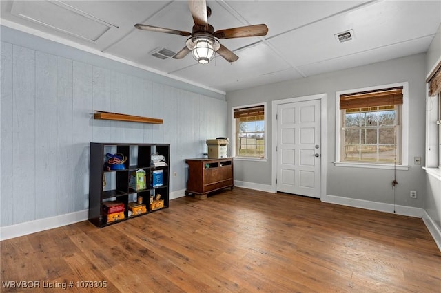 interior space featuring visible vents, wood-type flooring, baseboards, and ceiling fan