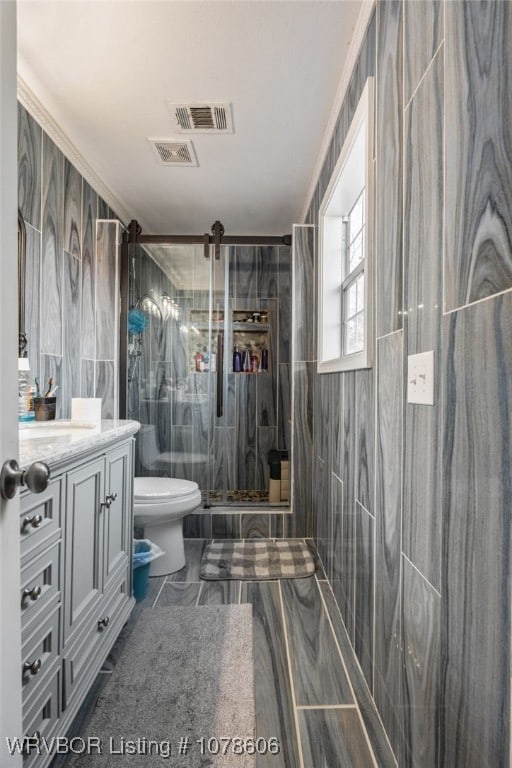 bathroom featuring tile walls, vanity, tiled shower, toilet, and crown molding