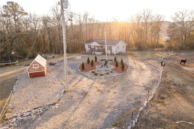 view of front of property with an outdoor structure and a trampoline