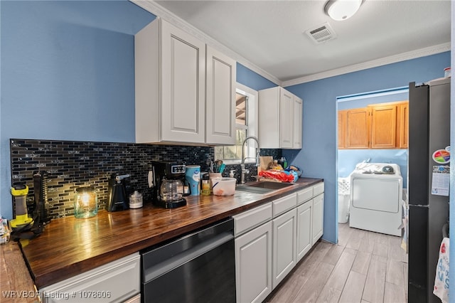 kitchen featuring butcher block counters, washer / dryer, white cabinetry, stainless steel refrigerator, and dishwasher