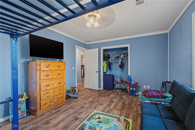 bedroom with ceiling fan, ornamental molding, hardwood / wood-style floors, and a closet