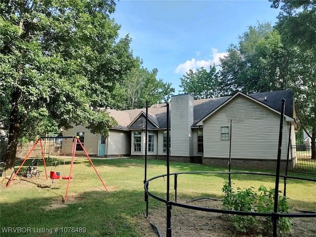 rear view of property featuring a playground and a yard