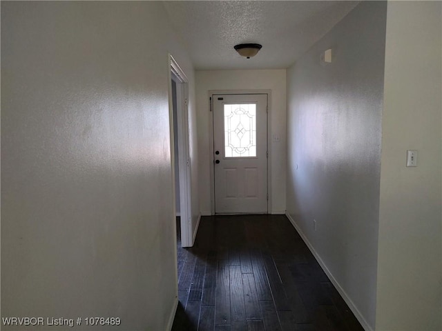 doorway to outside featuring a textured ceiling and dark hardwood / wood-style flooring