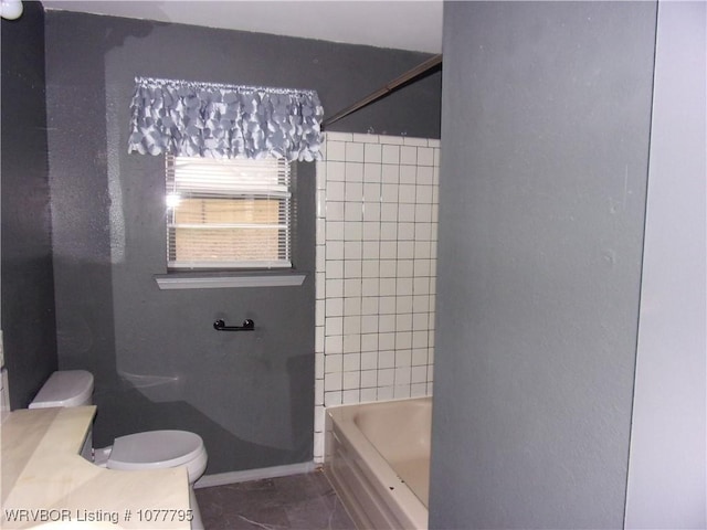 bathroom featuring tile patterned floors, toilet, and tiled shower / bath