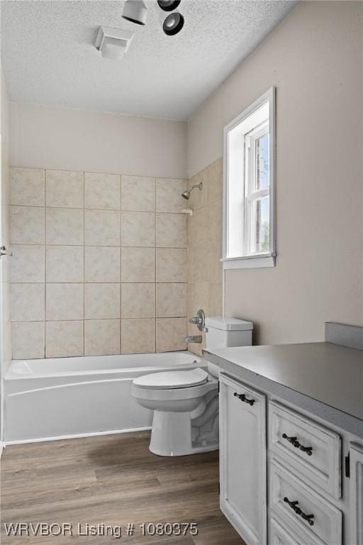 full bath with toilet, wood finished floors, a textured ceiling, and tub / shower combination