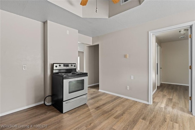 kitchen featuring light wood finished floors, baseboards, and electric stove