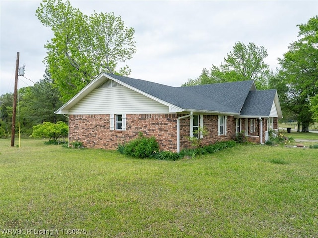 view of front of house featuring brick siding, a shingled roof, and a front yard