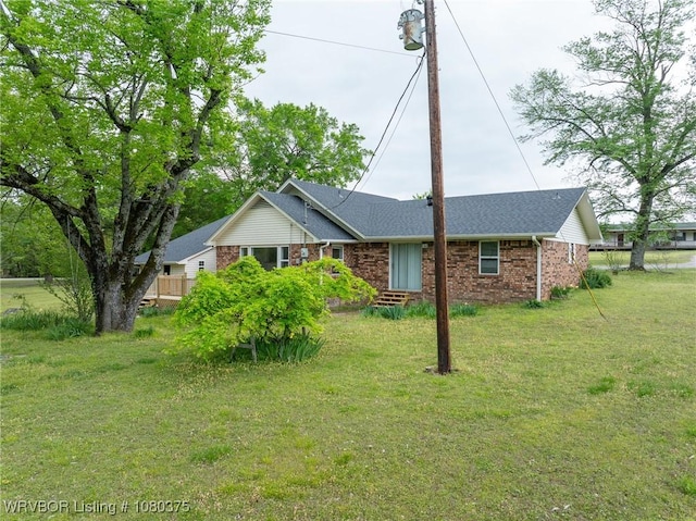 ranch-style house featuring brick siding, a front yard, and roof with shingles