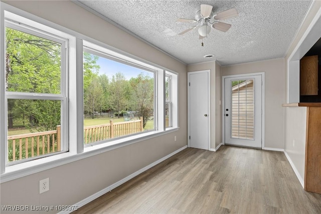 interior space featuring wood finished floors, a textured ceiling, a ceiling fan, and baseboards