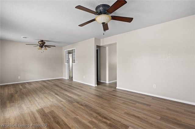 empty room with wood finished floors, a ceiling fan, and baseboards