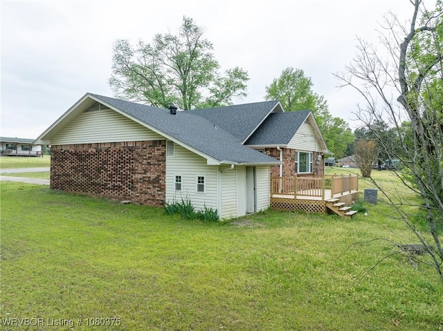 back of property with a lawn, brick siding, and a deck
