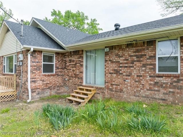 entrance to property with brick siding and roof with shingles