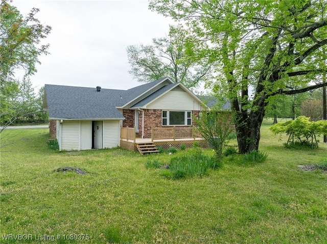rear view of house with brick siding, a lawn, a wooden deck, and roof with shingles