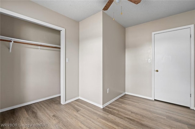 unfurnished bedroom with ceiling fan, baseboards, wood finished floors, and a closet