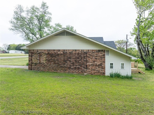 view of side of home featuring a lawn and brick siding