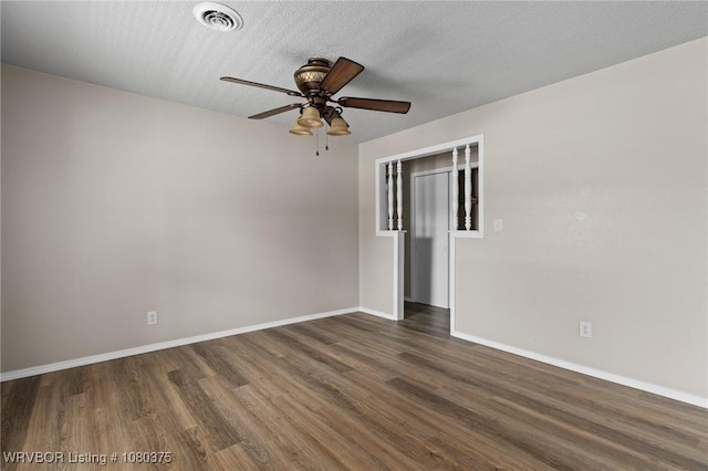 spare room with dark wood-type flooring, visible vents, a ceiling fan, and baseboards